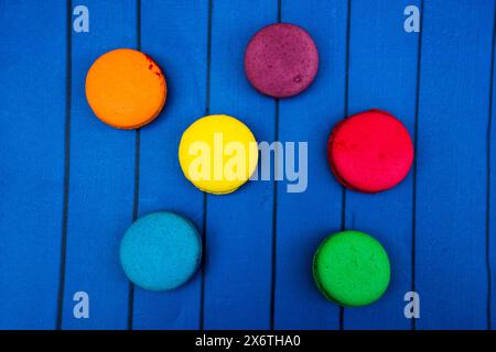 TopShot de macarons français doux et colorés sur fond en bois bleu. Banque D'Images