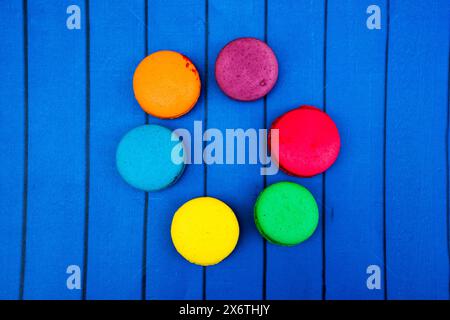 TopShot de macarons français doux et colorés sur fond en bois bleu. Banque D'Images