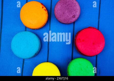 TopShot de macarons français doux et colorés sur fond en bois bleu. Banque D'Images