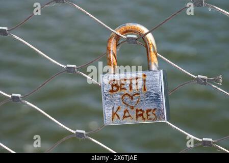 Cadenas rouillé, serrure d'amour, avec l'inscription Betti Herz Kares sur une balustrade de pont, symbole du vieil amour ne rouille pas, dans le fond l'eau de Banque D'Images