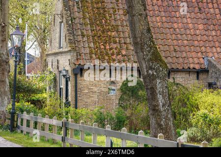 Maison historique avec mur de briques, clôture et lampadaire, entourée d'arbres et d'un jardin, maisons historiques dans un petit village avec de petites rues et Banque D'Images