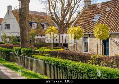 Maisons de village pittoresques avec des jardins bien entretenus et des clôtures vertes sous un ciel bleu, de vieilles maisons et de petites rues avec des lanternes et des arbres verts Banque D'Images