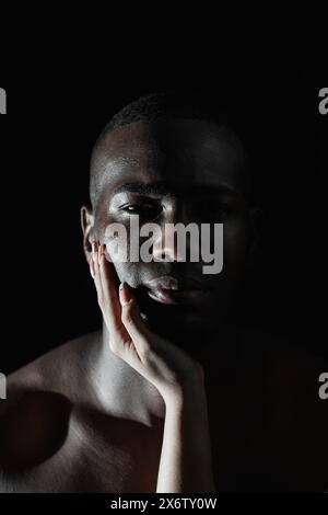 Gros plan du visage d'un homme afro-américain avec la main d'une femme caucasienne sur la joue. lumière à 90 degrés. Banque D'Images