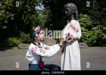 Une jeune fille vêtue de vyshyvanka (un vêtement traditionnel slave qui contient des éléments de broderie ethnique ukrainienne) habille le monument de la «mémoire amère de l'enfance» qui symbolise les victimes de l'Holodomor (famine) avec les mêmes vêtements à l'occasion de la Journée Vyshyvanka à Kiev. Banque D'Images