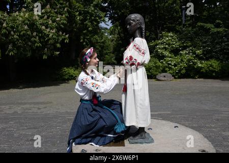 Une jeune fille vêtue de vyshyvanka (un vêtement traditionnel slave qui contient des éléments de broderie ethnique ukrainienne) habille le monument de la «mémoire amère de l'enfance» qui symbolise les victimes de l'Holodomor (famine) avec les mêmes vêtements à l'occasion de la Journée Vyshyvanka à Kiev. Banque D'Images