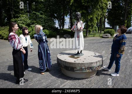 Les femmes vêtues de vyshyvankas (un vêtement traditionnel slave qui contient des éléments de broderie ethnique ukrainienne) regardent le monument «mémoire amère de l'enfance» qui symbolise les victimes de l'Holodomor (famine) vêtues des mêmes vêtements à l'occasion de la Journée de la Vyshyvanka à Kiev. Banque D'Images