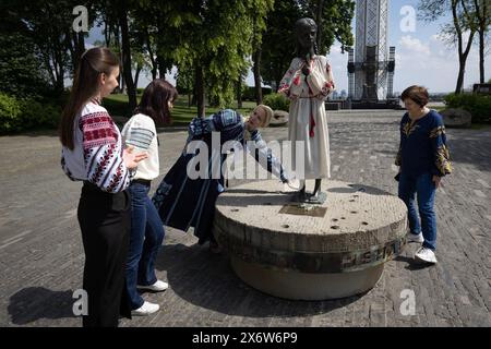 Les femmes vêtues de vyshyvankas (un vêtement traditionnel slave qui contient des éléments de broderie ethnique ukrainienne) regardent le monument «mémoire amère de l'enfance» qui symbolise les victimes de l'Holodomor (famine) vêtues des mêmes vêtements à l'occasion de la Journée de la Vyshyvanka à Kiev. Banque D'Images