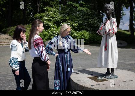 Les femmes vêtues de vyshyvankas (un vêtement traditionnel slave qui contient des éléments de broderie ethnique ukrainienne) regardent le monument «mémoire amère de l'enfance» qui symbolise les victimes de l'Holodomor (famine) vêtues des mêmes vêtements à l'occasion de la Journée de la Vyshyvanka à Kiev. Banque D'Images