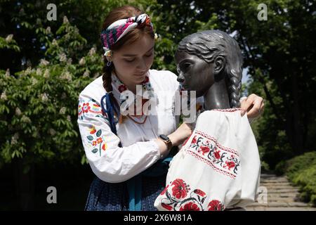 Kiev, Ukraine. 16 mai 2024. Une jeune fille vêtue de vyshyvanka (un vêtement traditionnel slave qui contient des éléments de broderie ethnique ukrainienne) habille le monument de la «mémoire amère de l'enfance» qui symbolise les victimes de l'Holodomor (famine) avec les mêmes vêtements à l'occasion de la Journée Vyshyvanka à Kiev. (Crédit image : © Oleksii Chumachenko/SOPA images via ZUMA Press Wire) USAGE ÉDITORIAL SEULEMENT! Non destiné à UN USAGE commercial ! Banque D'Images