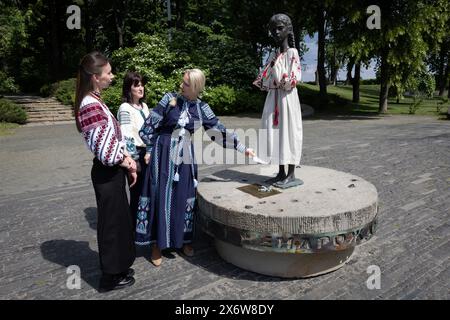 Kiev, Ukraine. 16 mai 2024. Les femmes vêtues de vyshyvankas (un vêtement traditionnel slave qui contient des éléments de broderie ethnique ukrainienne) regardent le monument «mémoire amère de l'enfance» qui symbolise les victimes de l'Holodomor (famine) vêtues des mêmes vêtements à l'occasion de la Journée de la Vyshyvanka à Kiev. (Photo de Oleksii Chumachenko/SOPA image/SIPA USA) crédit : SIPA USA/Alamy Live News Banque D'Images