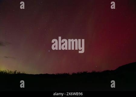 Faisceaux jaunes contre la lueur rouge d'Aurora Australis avec des faisceaux roses au-dessus de Matakaea (Shag point) dans l'île du Sud de la Nouvelle-Zélande pendant le largement Banque D'Images