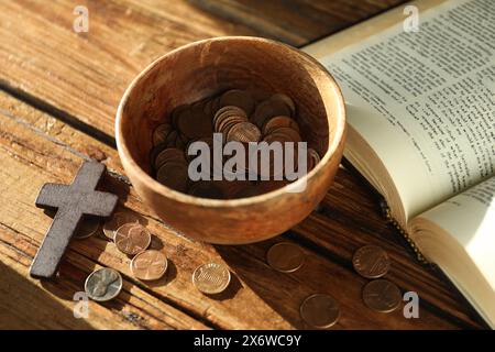 Donnez et donnez concept. Bol avec pièces de monnaie, croix et Bible sur table en bois Banque D'Images