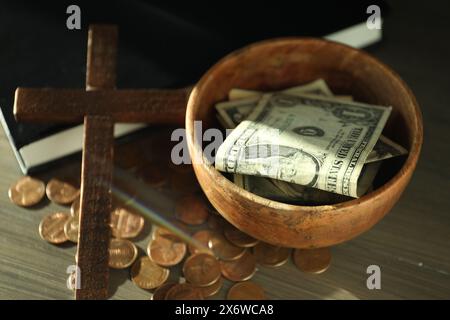 Donnez et donnez concept. Bol avec pièces de monnaie, billets de banque dollar, croix et Bible sur table en bois Banque D'Images