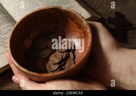 Donnez et donnez concept. Femme tenant un bol de pièces de monnaie à table, gros plan Banque D'Images