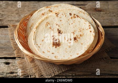 Tortillas maison savoureuses dans un panier en osier sur une table en bois Banque D'Images