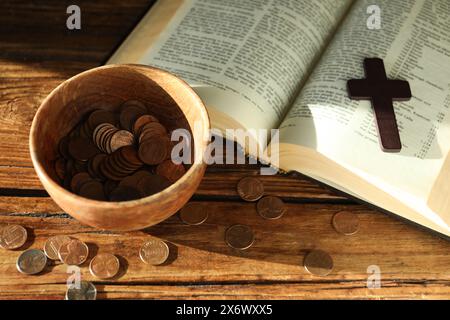 Donnez et donnez concept. Bol avec pièces de monnaie, croix et Bible sur table en bois Banque D'Images