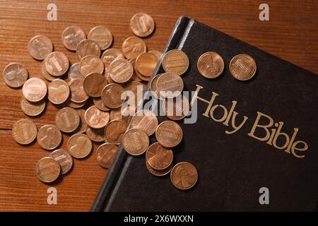 Donnez et donnez concept. Pièces de monnaie et Bible sur table en bois, plat Banque D'Images