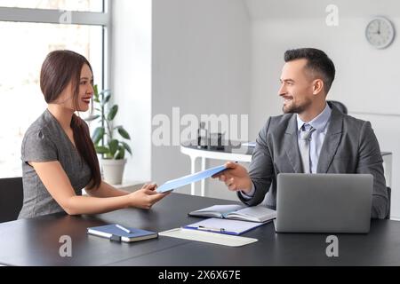 Demanderesse asiatique remettant son curriculum vitae au gestionnaire des ressources humaines lors de l'entrevue d'emploi au bureau Banque D'Images