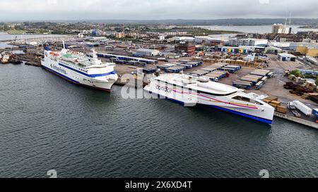 Tir par drone d'un port occupé avec un ferry de passagers amarré et des conteneurs de fret soigneusement disposés Banque D'Images