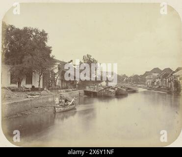 Vue du Kali Mas à Surabaya, vue du Kali Mas à Surabaya avec une barge avec des figures sur la gauche et un certain nombre de navires amarrés. A gauche une usine avec une grue et à droite une rangée de maisons sur la rivière. Une partie de l'album photo présenté par l'Association Soerabayasche des fabricants de sucre à Frederik Beyerinck, résident de Soerabaya., photographie, Herman Salzwedel, Soerabayasche Vereeniging van Suikerfabrikanten, Surabaya, 1876 - 1884, support photographique, tirage à l'albumine, hauteur, 21,8 cm × largeur, 27,2 cm Banque D'Images