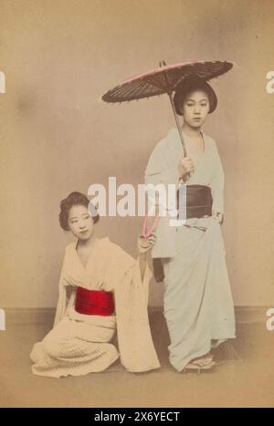 Double portrait de deux femmes japonaises inconnues, l'une des femmes est assise par terre et a une pantoufle dans la main gauche, l'autre femme est debout et a un parasol dans la main., photographie, anonyme, Japon, 1860 - 1900, papier, impression albumen, hauteur, 137 mm × largeur, 90 mm, hauteur, 170 mm × largeur, 113 mm Banque D'Images