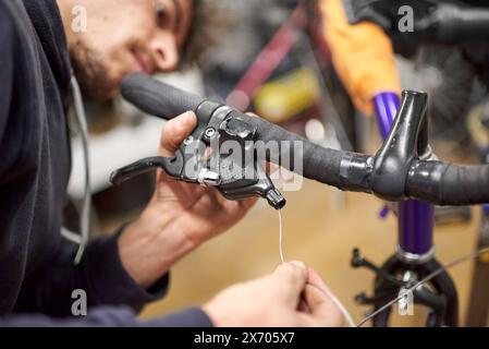 Réparateur hispanique assemblant le système de freinage d'un vélo dans le cadre du service d'entretien qu'il effectue dans son atelier. De vraies personnes au travail. Banque D'Images