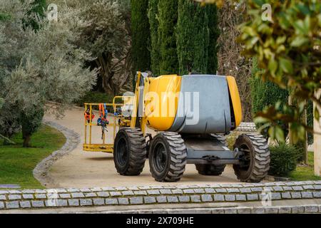 Ascenseur jaune à flèche utilisé par les ouvriers de la construction stationnés sur une passerelle dans un parc public. Madrid, Espagne. Banque D'Images