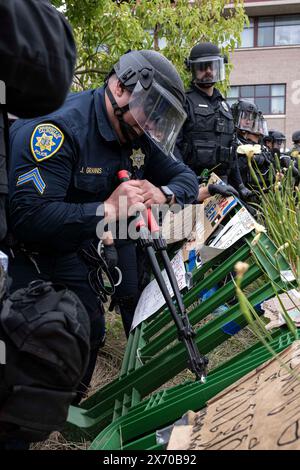 Irvine, Californie, États-Unis. 1er janvier 2023. Un policier de UC Irvine coupe les clips métalliques qui maintiennent la barrière du campement ensemble où les manifestants se sont barricadés à l'université. Des agents de nombreux services de police autour du comté d'Orange, en Californie, ont été appelés sur le campus d'Irvine de l'Université de Californie (UC) pour nettoyer un campement palestinien en pleine expansion prenant le contrôle du centre de l'Université. Les étudiants se barricadèrent en cercle, fortifiant leur périmètre avec des palettes de bois et divers autres objets pour empêcher les autorités d'entrer. Un total de 50 Banque D'Images