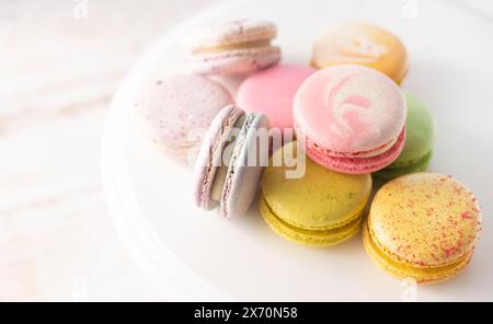 Macarons multicolores en gros plan sur fond de bois avec des lumières douces. Dessert français délicat pour le petit déjeuner à la lumière du matin. Banque D'Images