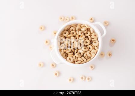 anneaux de céréales sains sur un fond blanc dans une assiette et dispersés sur la table. mangez le matin. Petit déjeuner sain pour enfants. Muesli sec. vue de dessus. Banque D'Images