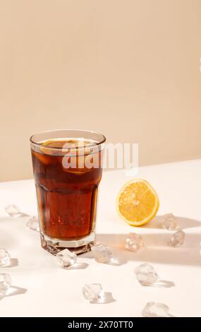 verre de boisson alcoolisée sur la table avec des glaçons et du citron. ombre longue. concept de fête et cocktail. rhum et cola. Banque D'Images
