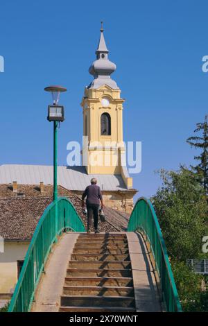 Vieille femme sur la passerelle menant à l'église de Saint Paul à bac, Voïvodine, Serbie Banque D'Images