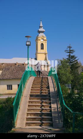 Vieille femme sur la passerelle menant à l'église de Saint Paul à bac, Voïvodine, Serbie Banque D'Images