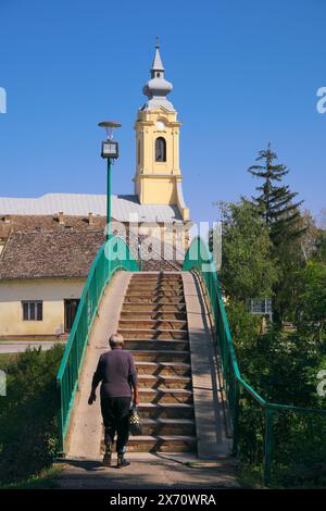 Vieille femme sur la passerelle menant à l'église de Saint Paul à bac, Voïvodine, Serbie Banque D'Images