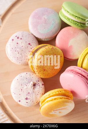 Macarons multicolores sur fond de bois avec des lumières douces et des ombres. Macarons doux sur table sur fond clair. Banque D'Images