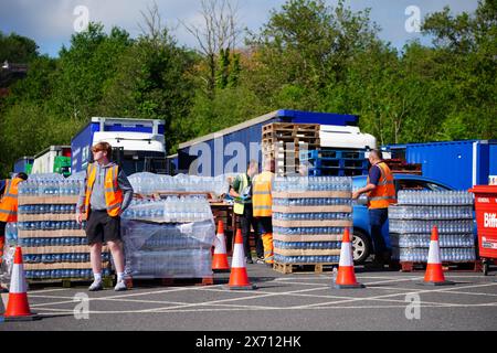 Les gens ramassent de l'eau en bouteille au parking Broadsands à Paignton. Environ 16 000 ménages et entreprises de la région de Brixham, dans le Devon, ont été priés de ne pas utiliser leur eau du robinet pour boire sans la faire bouillir et la refroidir d’abord, suite à la découverte de petites traces d’un parasite dans le réseau d’eau local. Date de la photo : vendredi 17 mai 2024. Banque D'Images