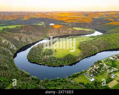 Vue aérienne du Solenice Horseshoe Bend sur la rivière Vltava en Tchéquie, montrant la rivière sinueuse entourée d'une végétation luxuriante et un petit village pendant un coucher de soleil pittoresque. Banque D'Images
