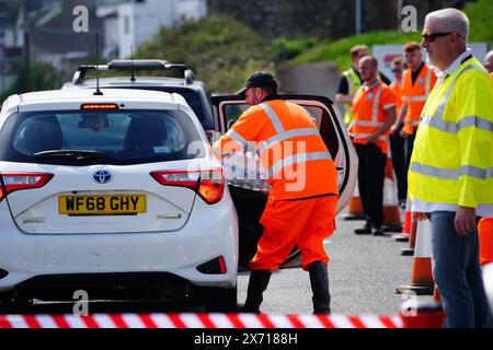 Les gens ramassent de l'eau en bouteille au parking Freshwater à Brixham. Environ 16 000 ménages et entreprises de la région de Brixham, dans le Devon, ont été priés de ne pas utiliser leur eau du robinet pour boire sans la faire bouillir et la refroidir d’abord, suite à la découverte de petites traces d’un parasite dans le réseau d’eau local. Date de la photo : vendredi 17 mai 2024. Banque D'Images