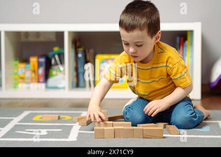 Petit garçon tout-petit mignon trois ans jouant des blocs de bois dans une chambre d'enfants à la maison. Jouets éducatifs pour enfants. Banque D'Images