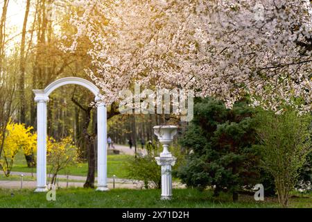 Belle vue sur un parc de la ville printanière avec des arbres fleuris, des buissons et une arche. Ukraine, Ivano-Frankivsk Banque D'Images