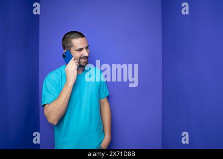 Heureux jeune homme parlant avec un téléphone portable sur fond de couleur Banque D'Images
