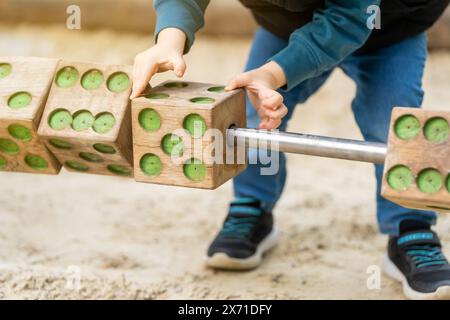 Mignon tout-petit garçon de trois ans joue sur l'aire de jeux avec des blocs de bois. Jeux pour enfants. Gros plan. Mise au point sélective Banque D'Images