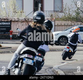 Haguenau, France - 20 mars 2024 : un groupe de jeunes sur des cyclomoteurs empruntent un virage dangereux dans la ville française de Haguenau. La scène capture le frisson et le risque de leur promenade aventureuse à travers les rues de la ville Banque D'Images