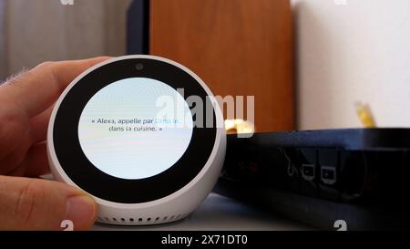 Paris, France - 5 juin 2020 : Amazon Echo Spot affiche des instructions en français pendant le processus de configuration, avec une main positionnée à proximité Banque D'Images