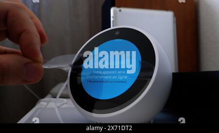 Paris, France - 5 juin 2020 : une main retire le film protecteur d'un Amazon Echo Spot lors du processus de configuration initial. Banque D'Images