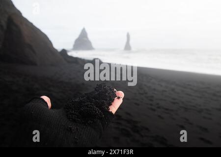 Gros plan sur le sable volcanique des touristes. Visitez Reynisfjara plage de sable noir toucher sable volcanique. Explorez le concept touristique de l'Islande Banque D'Images