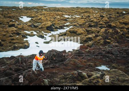 Touriste caucasien prenez des photos ou photographiez le paysage volcanique étonnant de mousse d'Eldhraun au coucher du soleil en Islande Banque D'Images