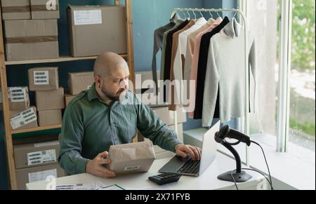 l'homme travaillant en heures supplémentaires écrit au client que le paquet est prêt. Il a un paquet dans la main. Banque D'Images