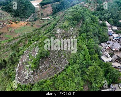 Qianxinan. 17 mai 2024. Une photo prise par un drone aérien le 17 mai 2024 montre une vue des ruines d'une ancienne ville datant de la dynastie Ming (1368-1644) au village de Pingzhai de la préfecture autonome de Bouyei-Miao de Qianxinan, dans la province du Guizhou au sud-ouest de la Chine. Le site apparaît de forme ovale vu d'en haut, couvrant une superficie d'environ 18 000 mètres carrés, avec plus de 900 mètres de murs de pierre restés. Crédit : Liu Xu/Xinhua/Alamy Live News Banque D'Images