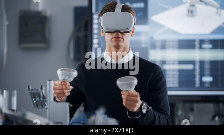 Étudiant masculin en lunettes VR soulevant et déplaçant la main bionique avec des contrôleurs tout en faisant son projet à l'Université de technologie. Concept d'enseignement de l'informatique et de la robotique. Banque D'Images